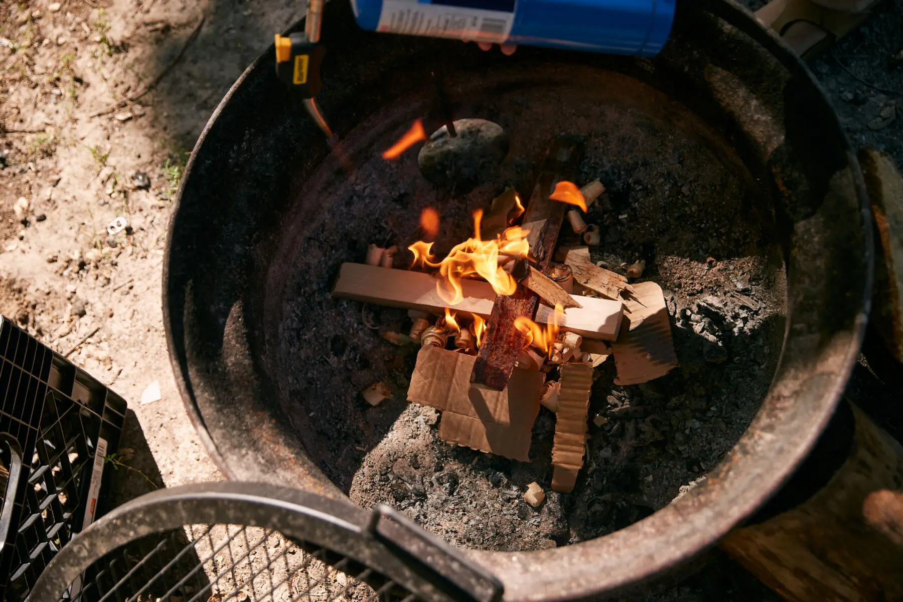 hands lighting dry tinder at the base of a campfire