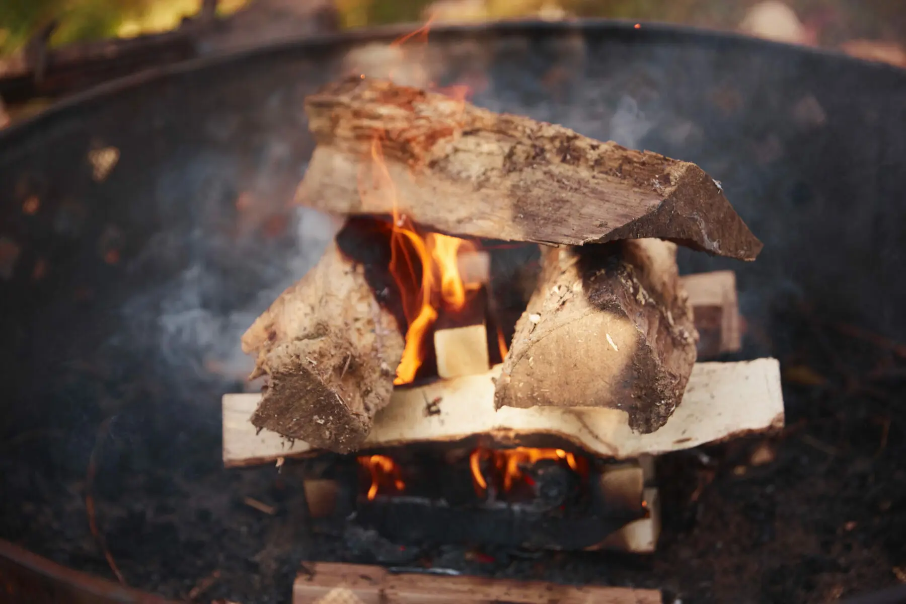 log cabin style campfire stack ready to light in a stone fire ring