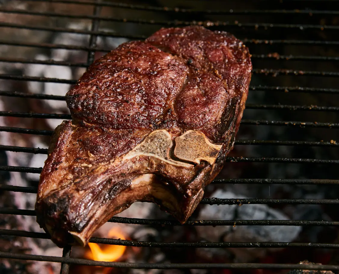 Perfect Campfire Steak: Thick Ribeye Over the Embers 1 Perfect campfire steak, a thick bone-in ribeye resting after grilling over embers