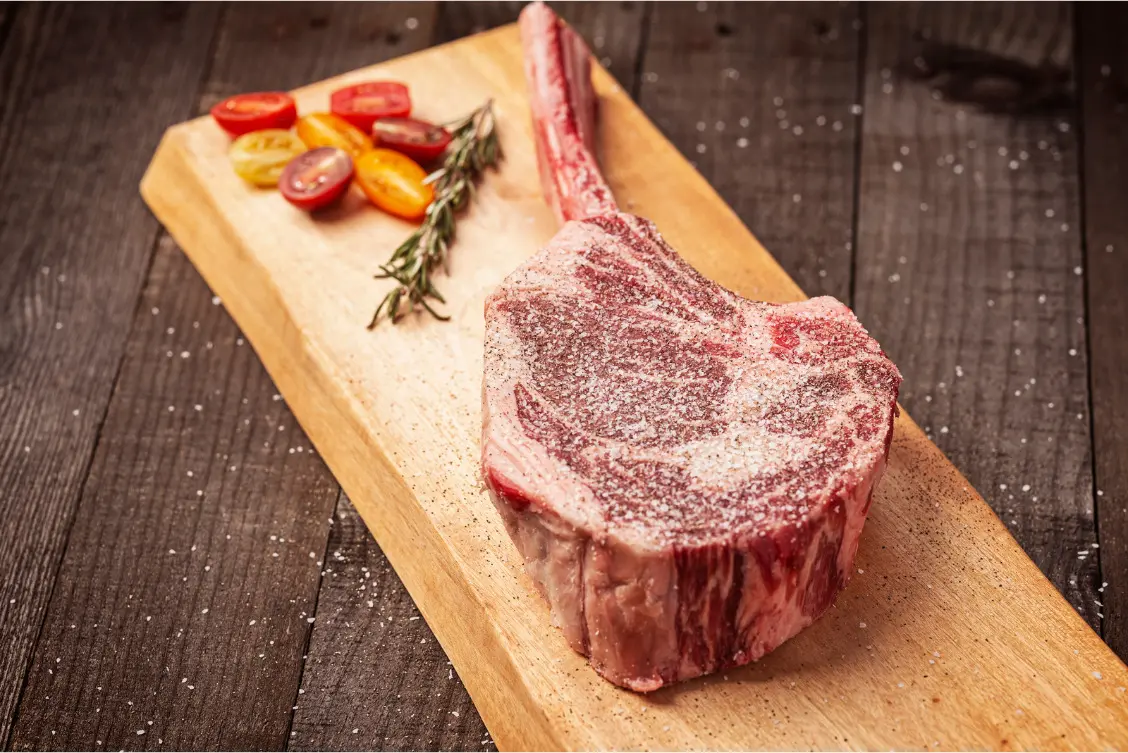 Perfect Campfire Steak: Thick Ribeye Over the Embers 2 A thick raw bone-in ribeye steak with heavy marbling