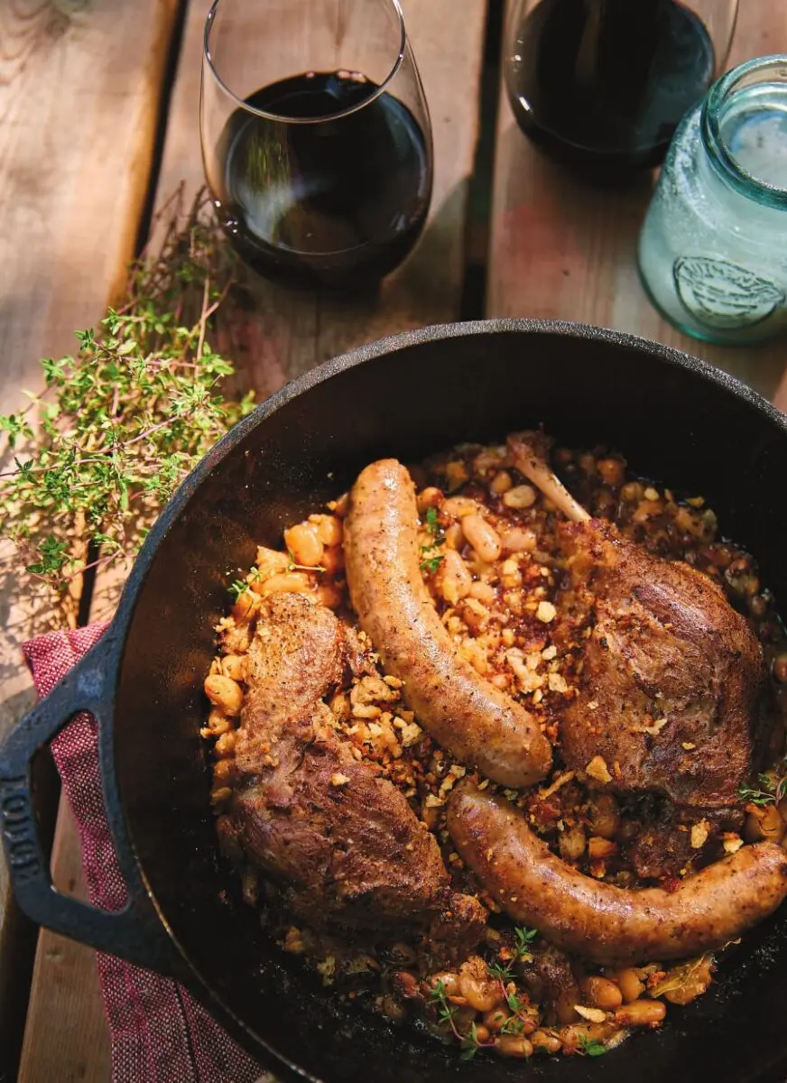 Campfire cassoulet in a cast iron pot with duck confit, Toulouse sausage and cannellini beans, topped with garlic breadcrumbs over the coals