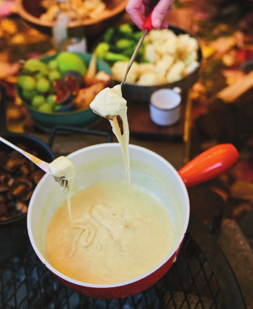 Campfire Cheese Fondue 1 Pot of melted Gruyere and Vacherin cheese fondue with bread cubes, set over campfire embers