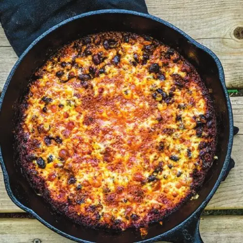 Beans au Gratin 2 Beans au gratin in a cast iron pan, black beans under a torched golden cheese crust over the fire