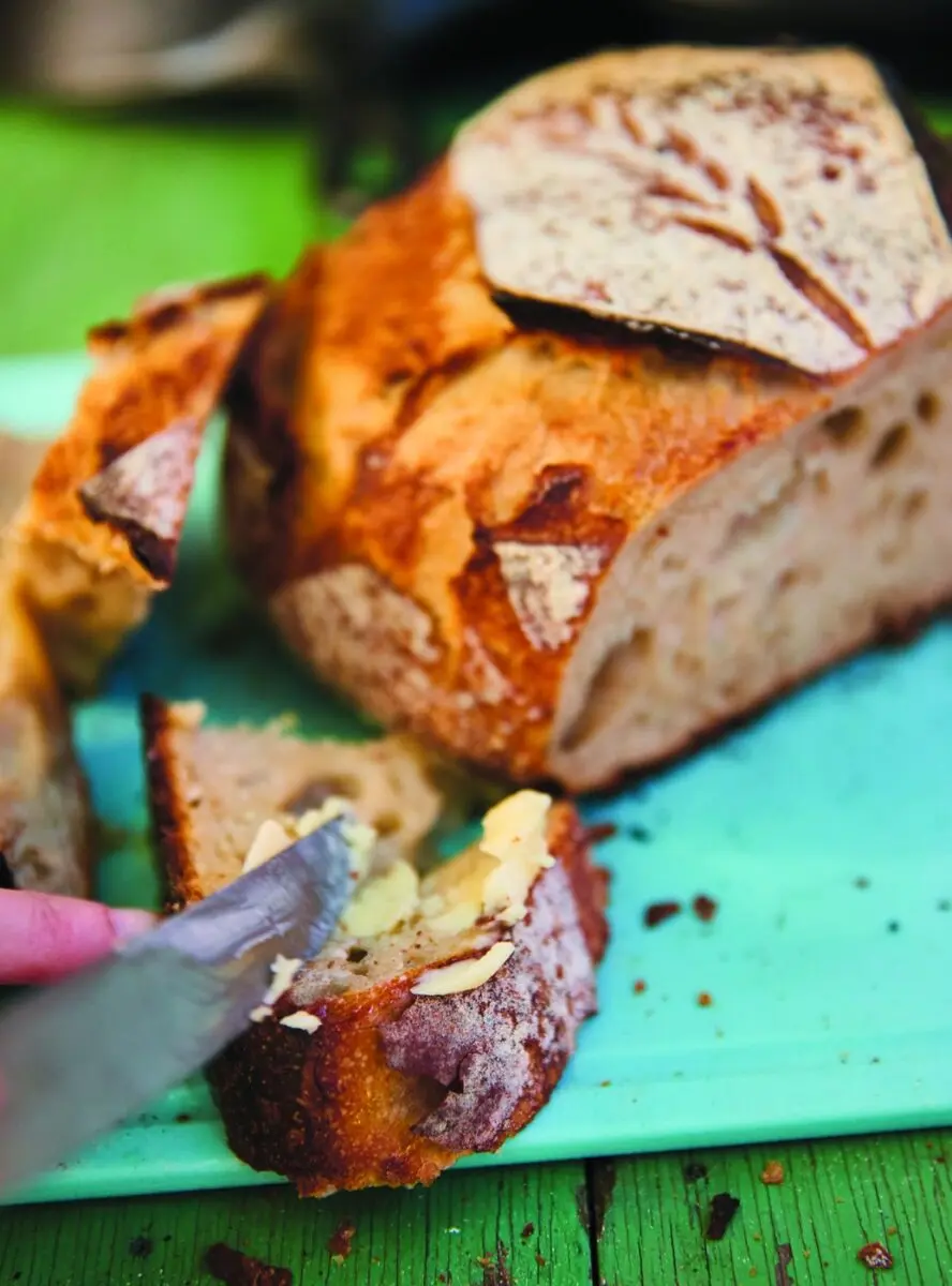 Dutch Oven Bread 3 Sliced dutch oven bread on a turquoise board, one slice spread with butter