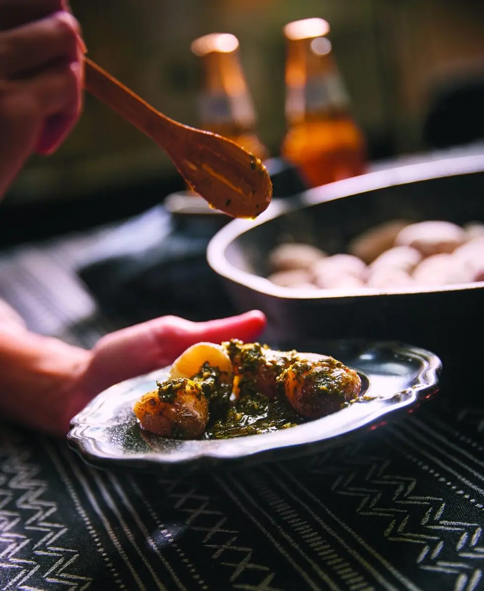 Salt-crusted potatoes served on a plate with green herb sauce spooned over