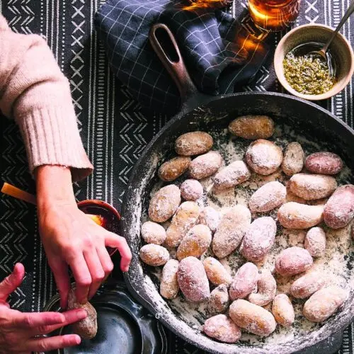 Salt-crusted potatoes in a cast iron pan with mojo rojo and mojo verde alongside